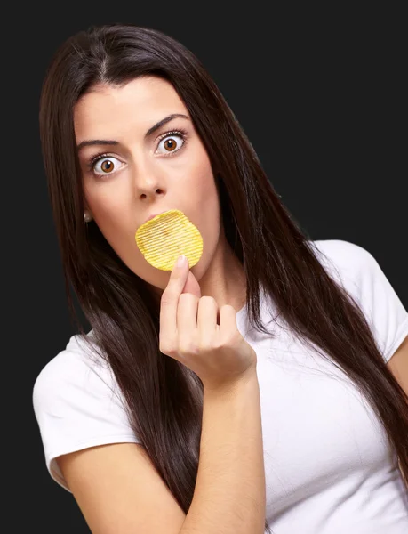 Porträt einer jungen Frau, die sich Kartoffelchips über den Mund hält — Stockfoto