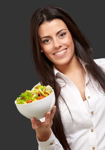 Portrait of young woman holding salad over black — Stock Photo, Image