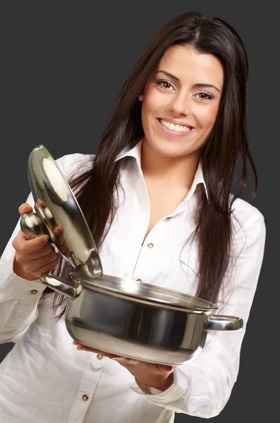 Portrait of young girl opening sauce pan over black background — Stock Photo, Image
