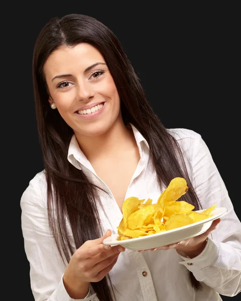 Porträt einer jungen Frau, die einen Kartoffelchips-Teller über Schwarz hält — Stockfoto