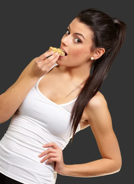 Gezonde meisje een granen bar eten op zwarte achtergrond — Stockfoto