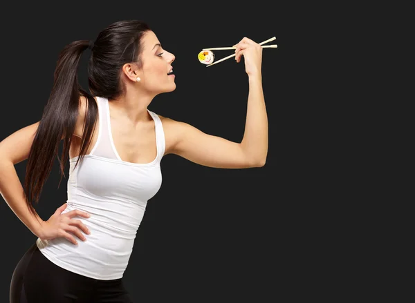 Junge hübsche Frau isst Sushi auf schwarzem Hintergrund — Stockfoto