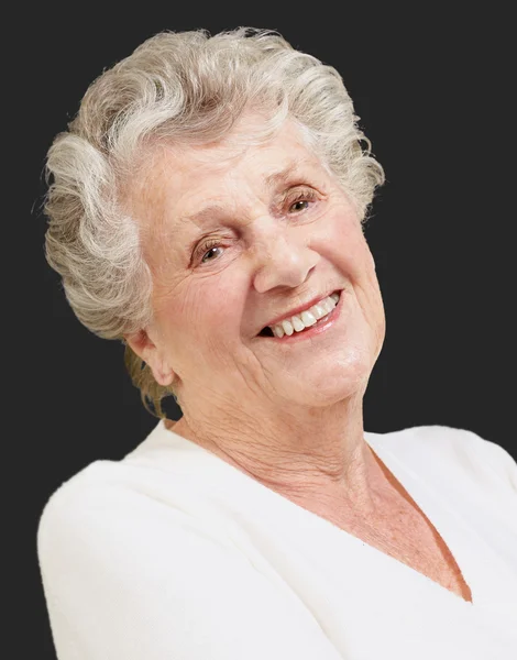 Портрет пожилой женщины, улыбающейся на черном фоне — стоковое фото