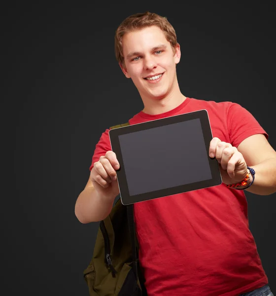 Retrato de un joven sosteniendo una tableta digital sobre fondo negro Imagen de stock