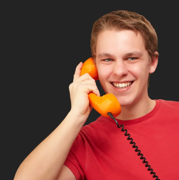 Portrait of young man talking with vintage telephone over black Royalty Free Stock Images