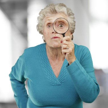 Portrait of senior woman looking through a magnifying glass, ind clipart