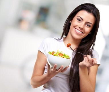 Portrait of healthy woman eating salad indoor clipart