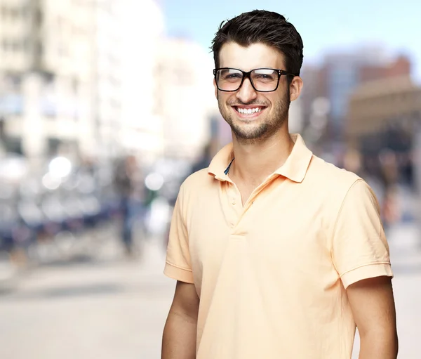 Портрет милого молодого человека, улыбающегося на оживленной улице — стоковое фото