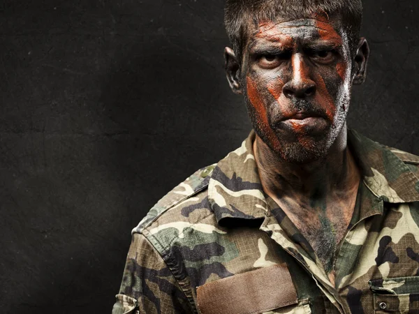 Joven soldado con pintura de camuflaje que se ve muy serio contra —  Fotos de Stock