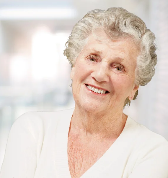 Portrait of senior woman smiling against a abstract background — Stock Photo, Image