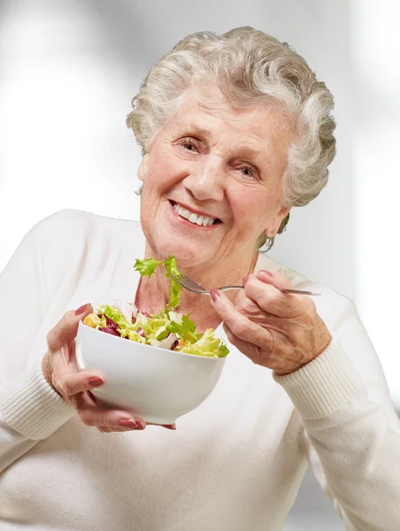 Ritratto di donna anziana che mangia un'insalata fresca al coperto — Foto Stock