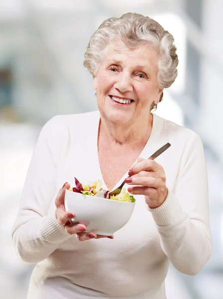 Portrét starší ženy jíst salát vnitřní — Stock fotografie