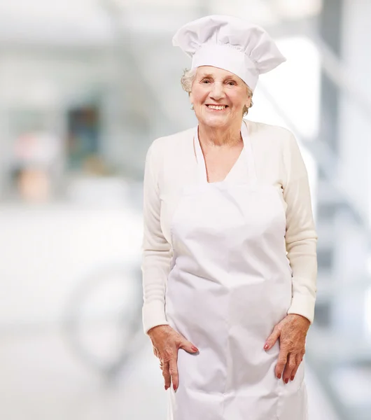 Портрет повара пожилой женщины, улыбающейся в помещении — стоковое фото