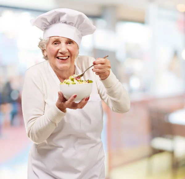 Porträtt av senior kock kvinna äta på restaurang — Stockfoto