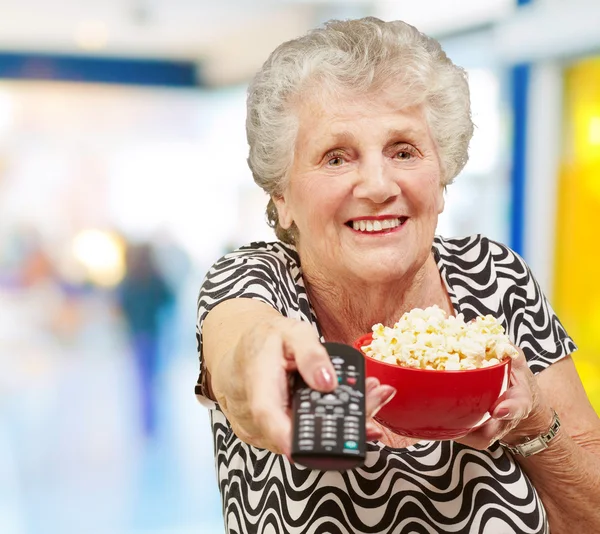 Portrét starší ženy držící misku popcorn a změnou chan — Stock fotografie