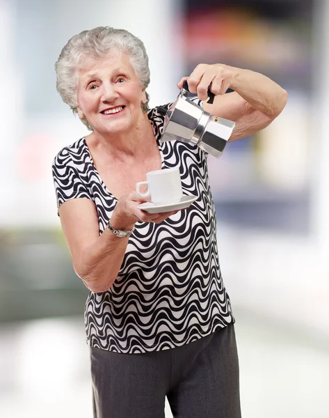 Porträt einer vitalen Seniorin, die im Haus eine Teetasse serviert — Stockfoto