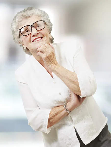 Портрет пожилой женщины, думающей и смотрящей вверх, в помещении — стоковое фото