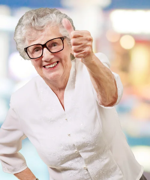 Ritratto di adorabile donna anziana che fa un buon gesto contro una a — Foto Stock