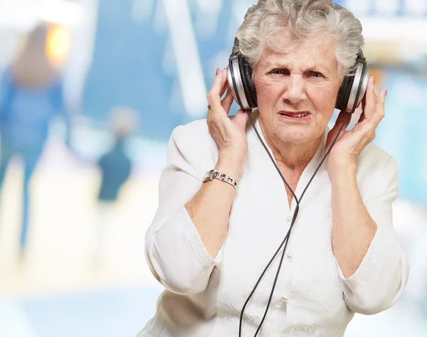 Portrait of senior woman listening to music indoor — Stock Photo, Image