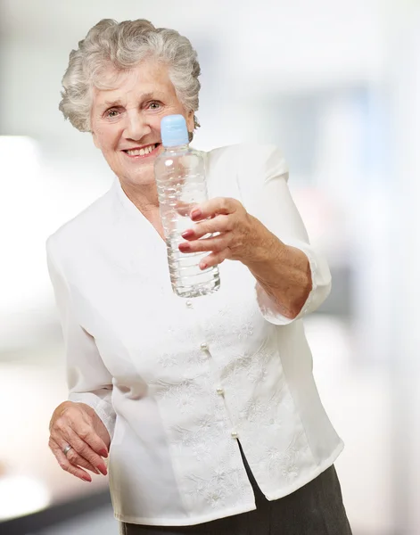 Retrato de mulher idosa saudável segurando uma garrafa de água interior — Fotografia de Stock