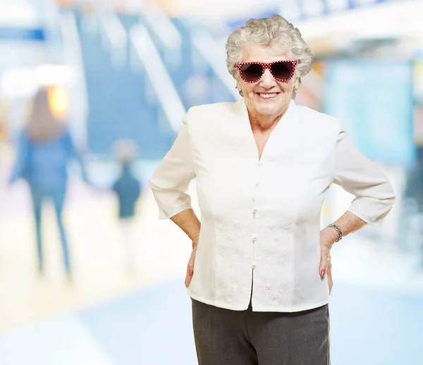 Портрет пожилой женщины, улыбающейся и в солнечных очках в торговом центре — стоковое фото