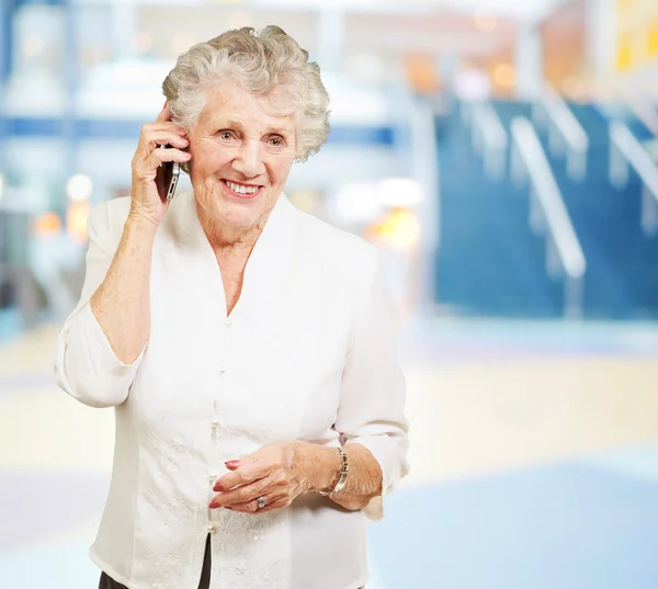 Porträt einer Seniorin im Handy-Gespräch in Einkaufszentrum — Stockfoto