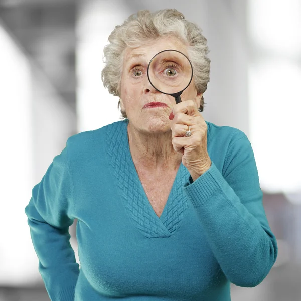 Portrait of senior woman looking through a magnifying glass, ind — Stock Photo, Image