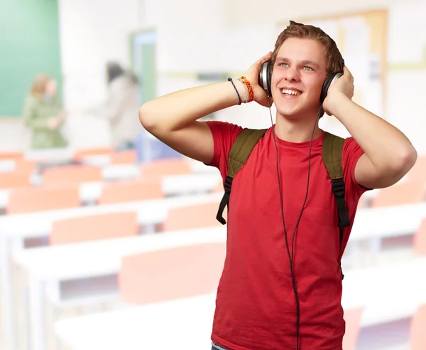 Porträt einer fröhlichen jungen Studentin, die Musik mit Kopfhörer hört — Stockfoto