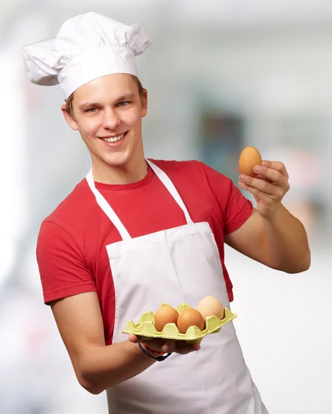年轻厨师该名男子手持鸡蛋盒室内的肖像 — 图库照片