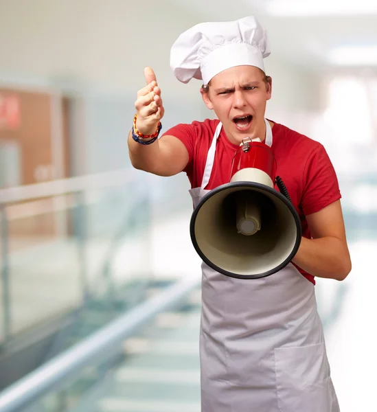 Retrato del joven cocinero gritando con megáfono y gesturín — Foto de Stock