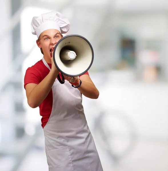 Retrato del joven cocinero gritando con megáfono interior — Foto de Stock