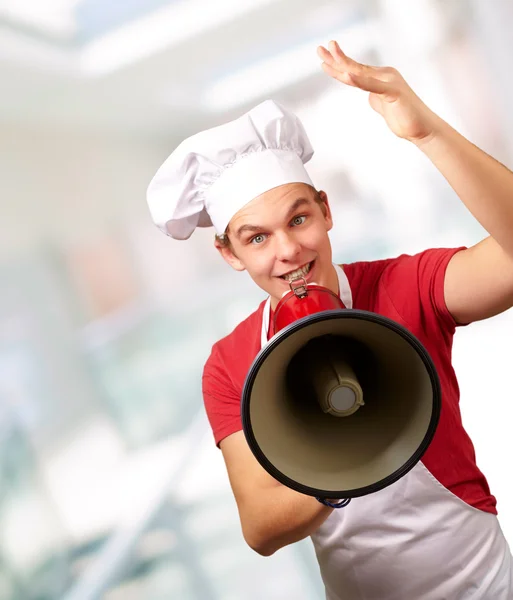Retrato de homem cozinheiro feliz gritando usando megafone interior — Fotografia de Stock