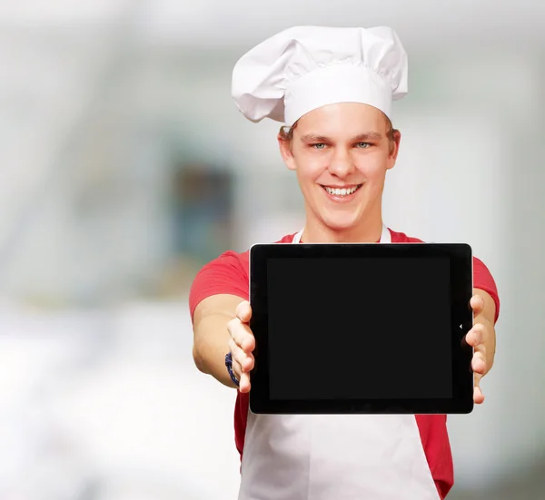 Портрет молодого кухаря, який показує цифровий планшет у приміщенні — стокове фото
