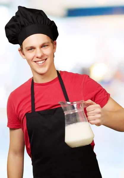 Portrait of young cook man holding milk jar indoor