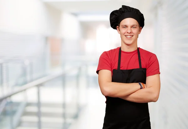 Retrato de jovem cozinheiro vestindo uniforme e sorrindo contra um — Fotografia de Stock