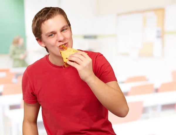 Porträt eines jungen Mannes, der im Klassenzimmer Pizza isst — Stockfoto
