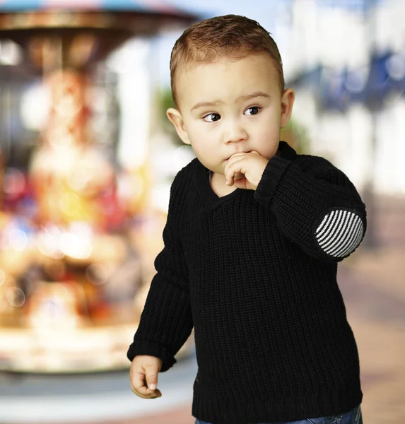 Retrato de niño adorable pensando cerca del carrusel —  Fotos de Stock