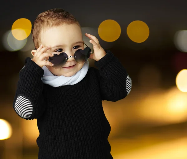 Portrait of funny kid wearing heart sunglasses at city by night — Stock Photo, Image