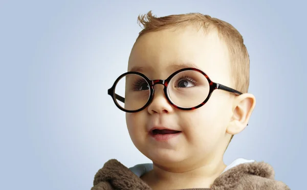 Porträt eines süßen Kindes mit runder Brille vor blauem Hintergrund — Stockfoto