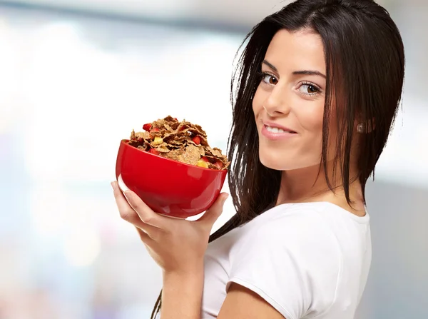Retrato de mujer joven sosteniendo un tazón de cereal en el interior —  Fotos de Stock
