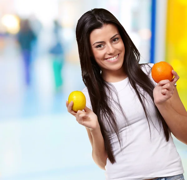 Mladá hezká holka drží pomeranč a citron vnitřní — Stock fotografie