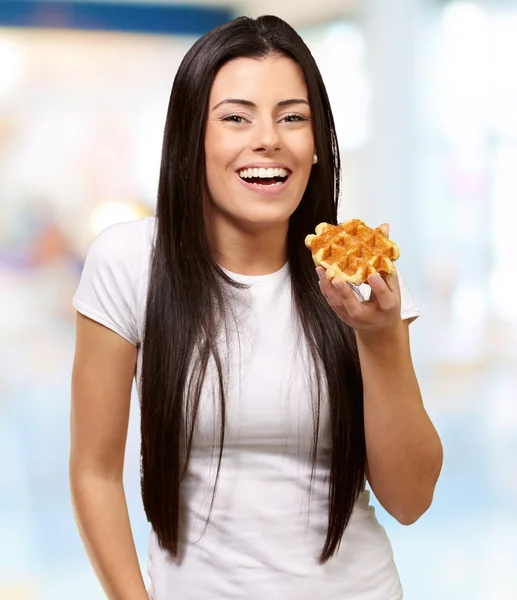 Portrait of young woman holding waffle indoor — Stock Photo, Image