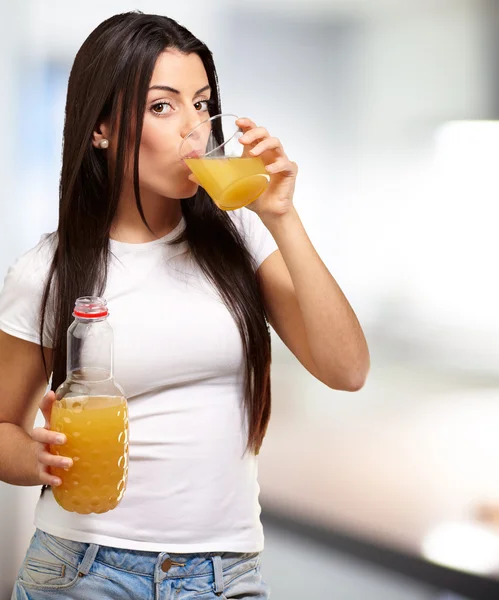Портрет молодой девушки, пьющей апельсиновый сок в помещении — стоковое фото