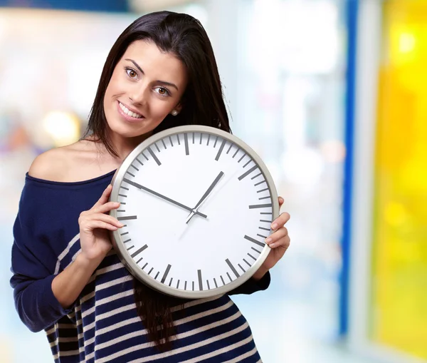 Portrait of young woman holding clock indoor — Stock Photo, Image