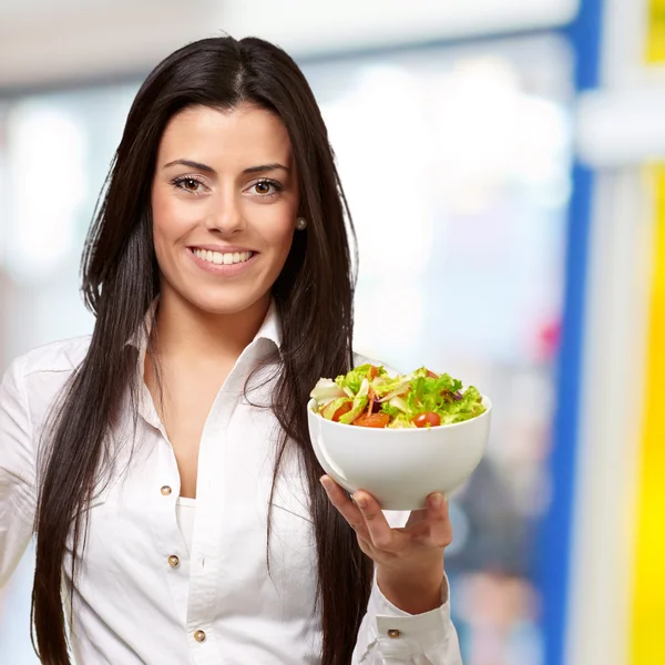 Portret van een jonge vrouw met salade binnen — Stockfoto