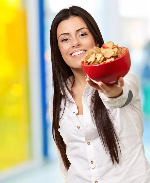 Portrait of young woman offering cereals bowl indoor — Stock Photo, Image