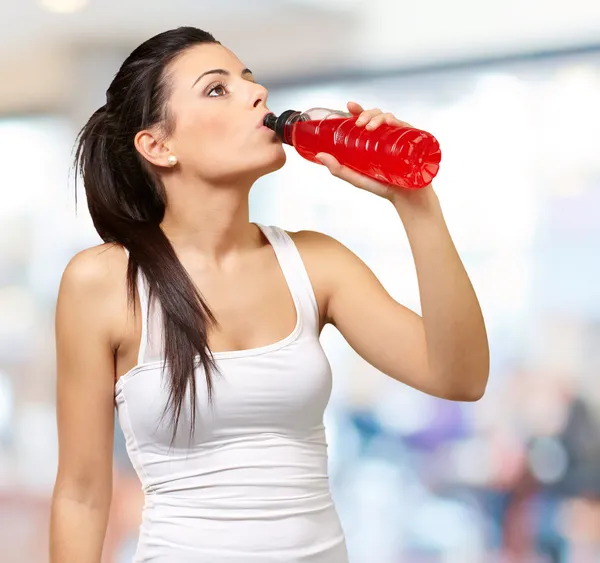 Portrait of young sporty woman drinking isotonic drink indoor — Stock Photo, Image