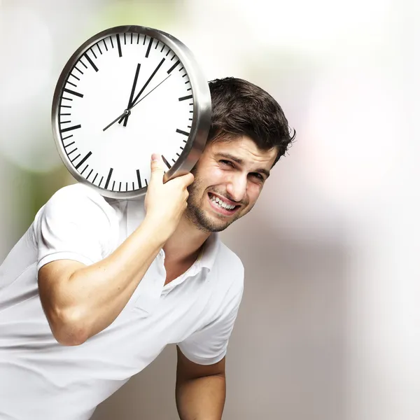 Portret van een knappe jonge man met een klok tegen een onscherpe achtergrond Stockfoto