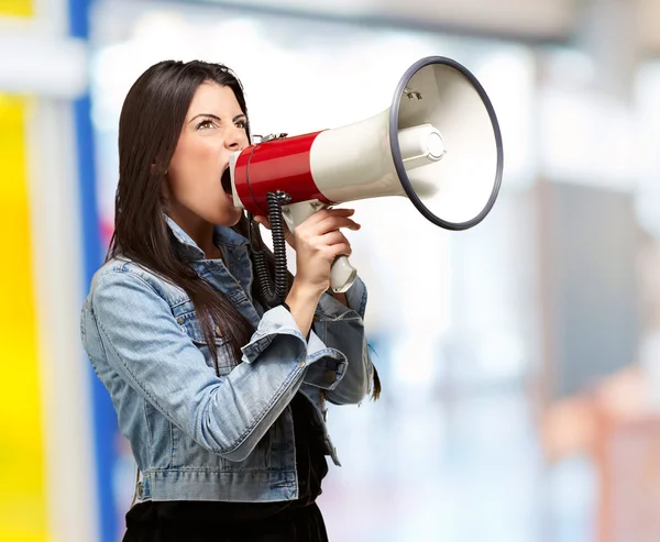 Portrait of young woman screaming with megaphone indoor Royalty Free Stock Images