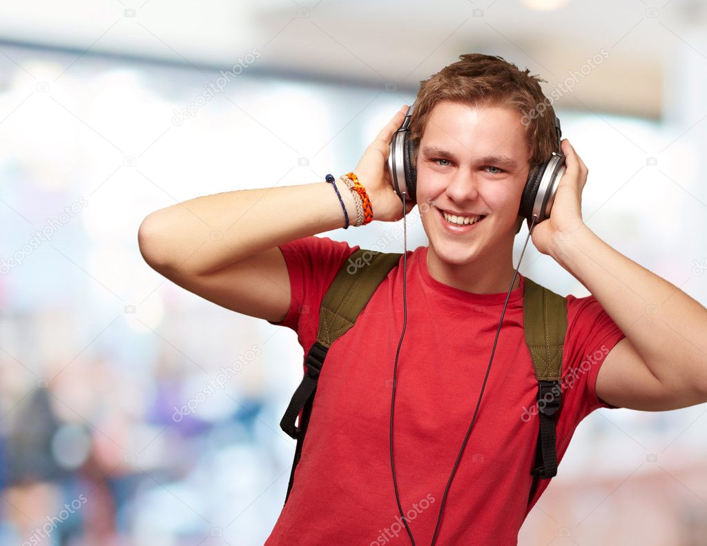 Portrait of cheerful young student listening music with headphon